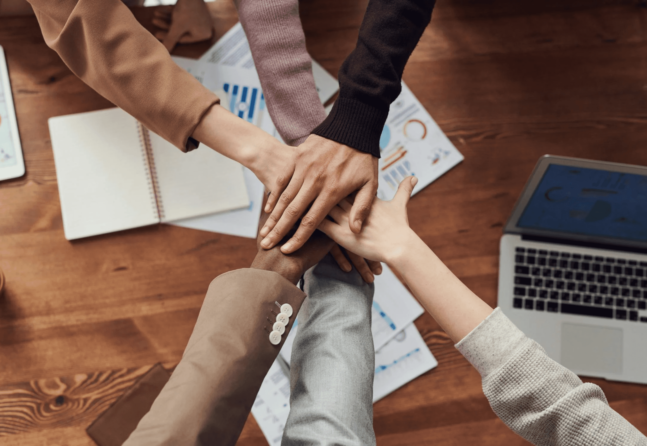 Team hands stacked together over planning materials